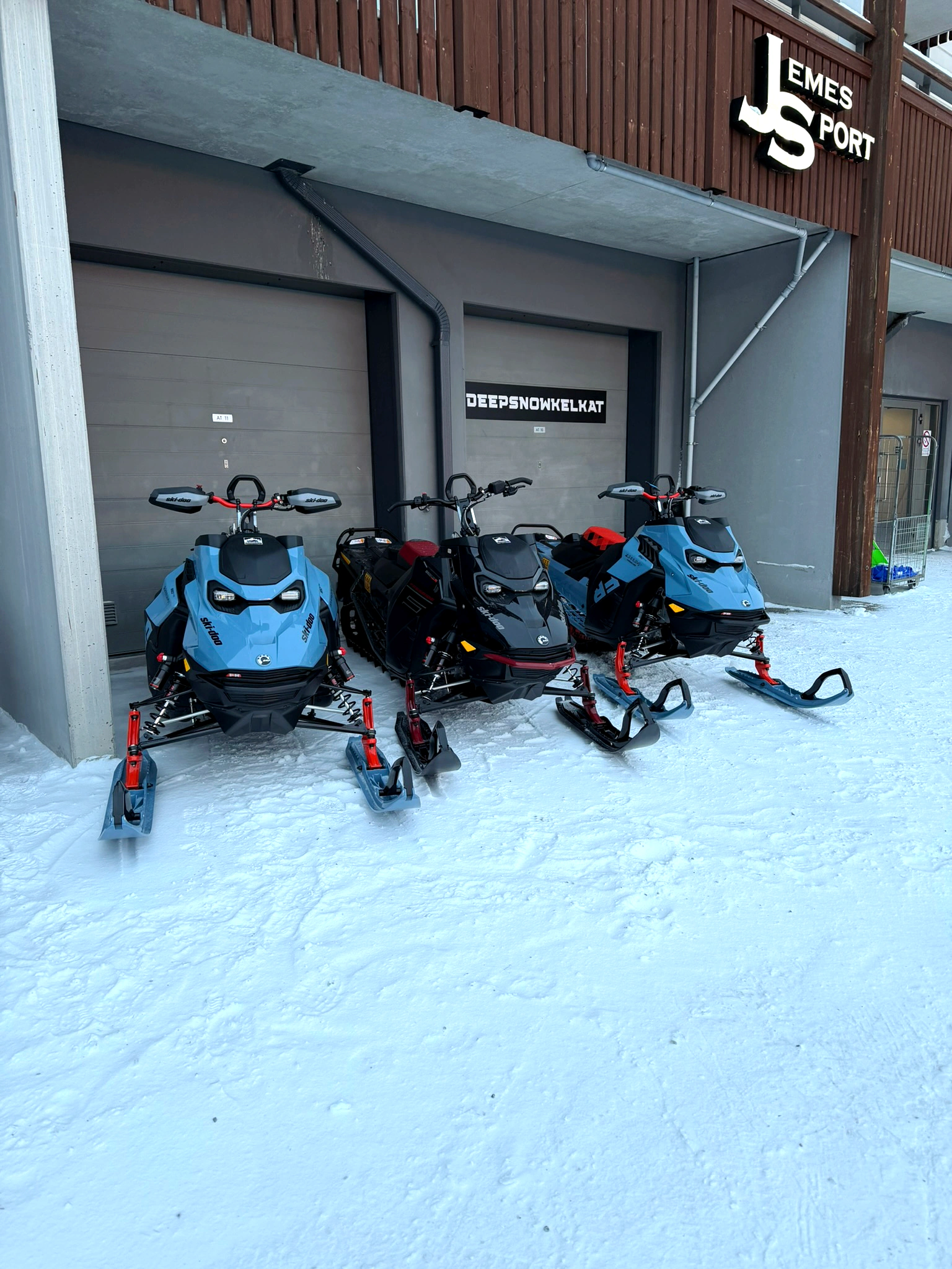 Deepsnowkelkat snowmobiles lined up outside the rental garage