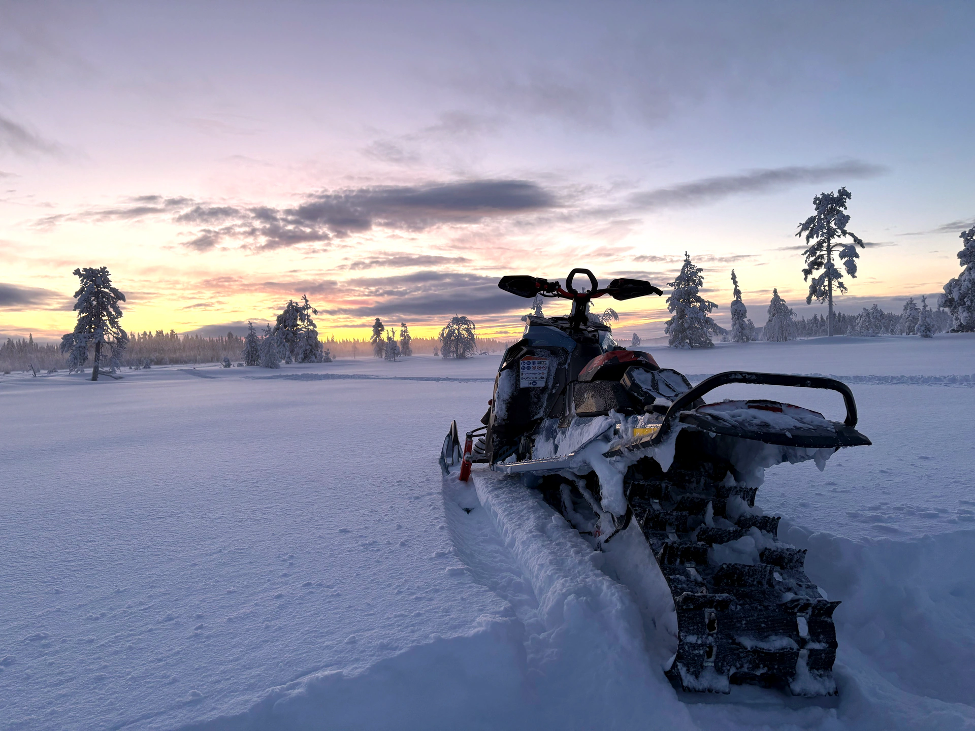 Snowmobilers riding through a snowy Lapland landscape